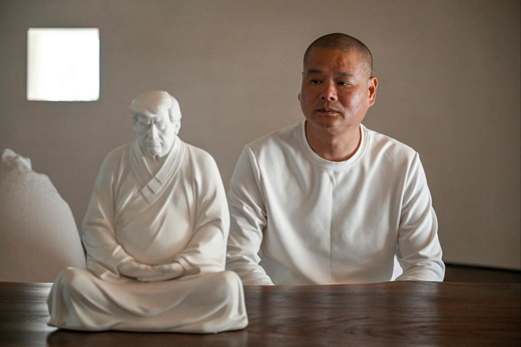 Chinese artist Hong Jinshi sitting next to a sculpture of US president-elect Donald Trump in a pose evoking the Buddha. Photo: AFP
