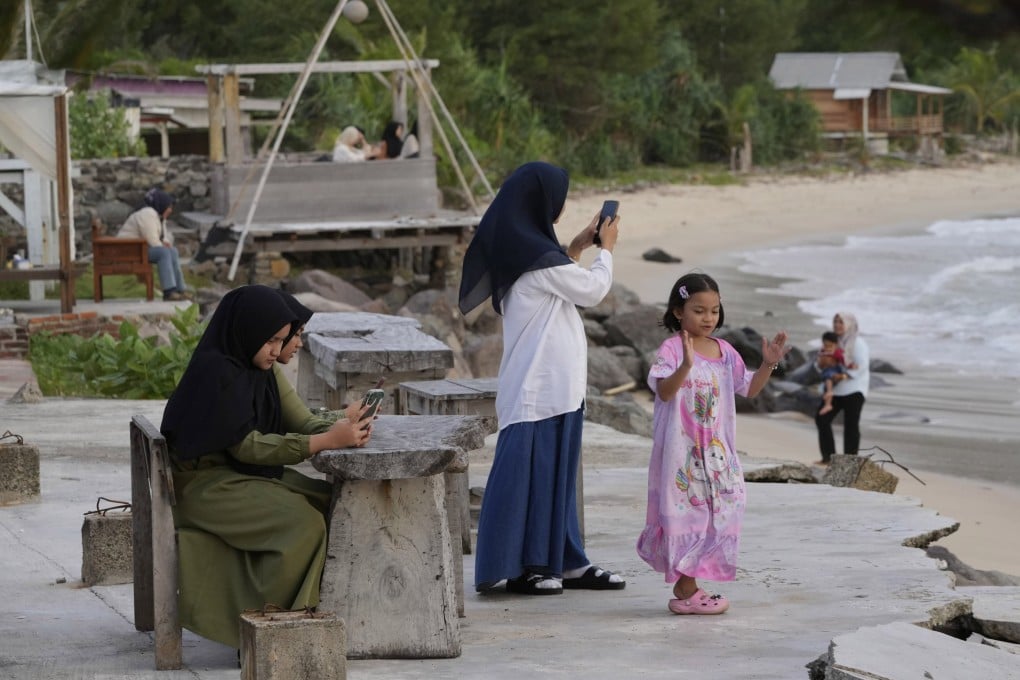 Young girls use their mobile phones as they visit Lampuuk beach on the outskirts of Banda Aceh, Indonesia, in December 2024. Photo: AP