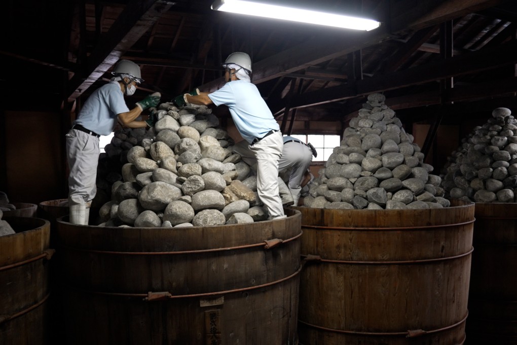 Workers at Kakukyu Hatcho Miso’s production plant in Nagoya, Japan, stacking rocks on casks of fermenting miso. Each cask lid is weighed down with three tonnes of rocks. Photo: Llewellyn Cheung