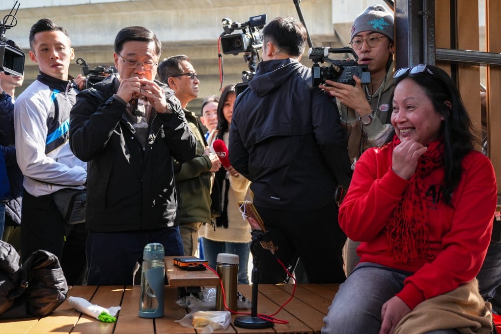 Chief Executive John Lee takes a bite of some sticky rice dessert as he chats with domestic helpers. Photo: Eugene Lee