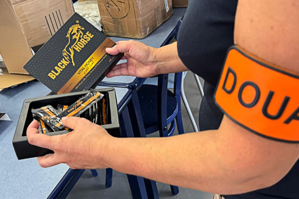 A French customs officer holds packs of illegally imported “Black Horse” honey touted as an all-natural sexual enhancement. Photo: Douanes Francaises/AFP