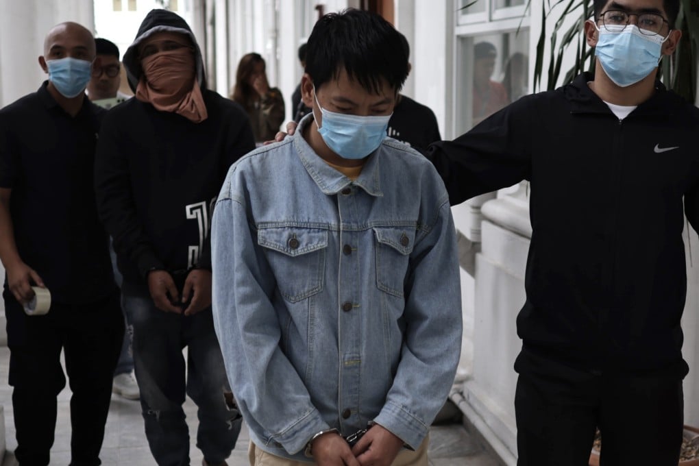 Chinese national Deng Yuanqing (middle) with an unidentified Filipino companion in handcuffs escorted to the Department of Justice office in Manila on Monday. Photo: EPA-EFE