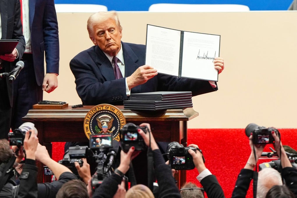 US President Donald Trump holds up an executive order after signing it at an indoor presidential inauguration event in Washington on Monday. Photo: AP