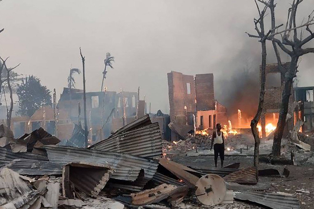 A man stands amid burning rubble at the site of a suspected air strike carried out by Myanmar’s military in western Rakhine state. Photo: Arakan Army / AFP