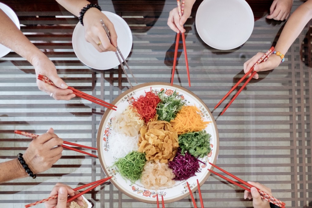 A Malaysian Chinese family prepares to toss the ingredients of “yusheng” or prosperity toss salad, a Chinese New Year ritual said to bring luck and good fortune. Photo: Getty Images