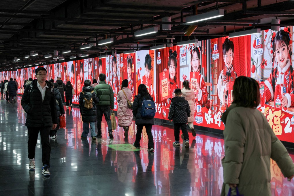People walk past a row of billboards in a metro station in Shanghai. Retail sales in the city fell in 2024 as consumers remain reluctant to spend. Photo: Reuters