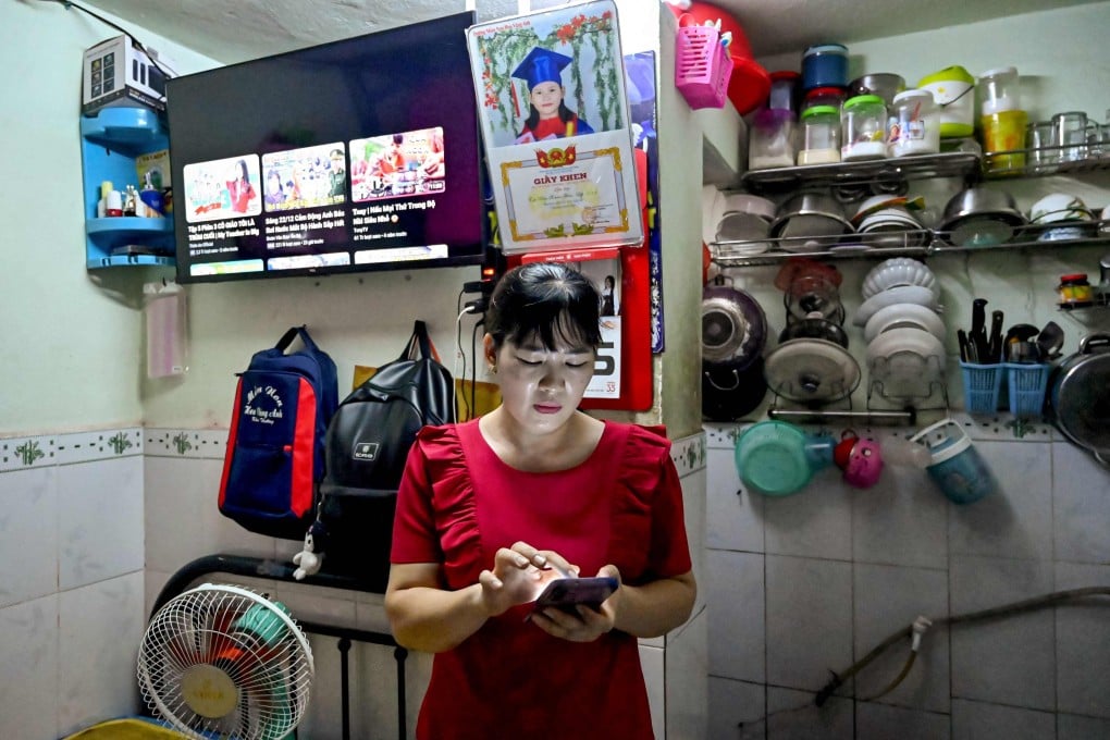 Nguyen Thi Hiep, who works at Taiwanese shoemaker Pou Chen’s Pouyuen Vietnam factory, checks her mobile phone as she stands in her 10-square-metre, one-room apartment in Ho Chi Minh City, Vietnam. Photo: AFP