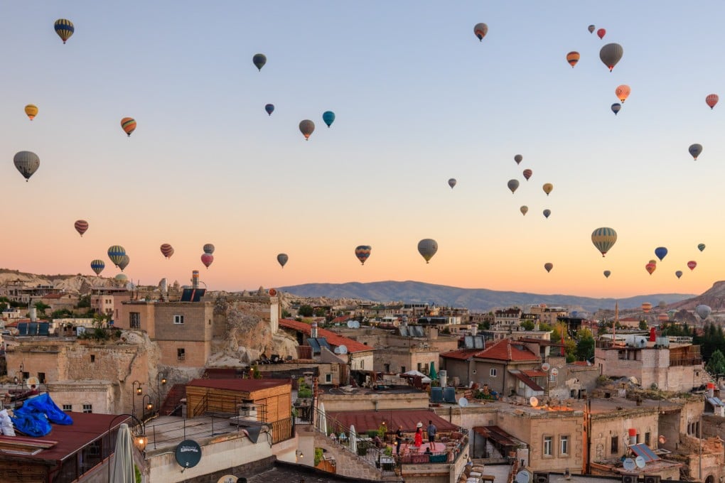 Travellers taking photos of hot-air balloons in flight in the town of Göreme in the early morning in Turkey. Photo: Shutterstock