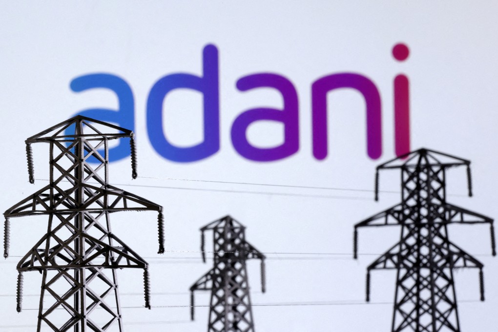 Electric power transmission pylon miniatures and the Adani Green Energy logo. Photo: Reuters