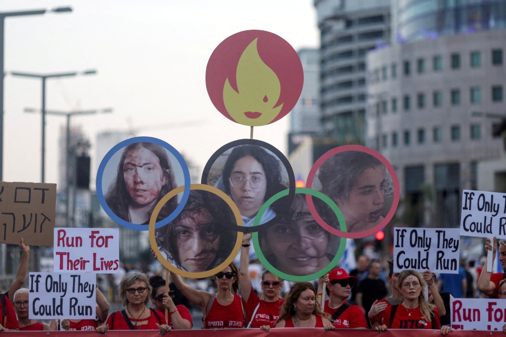 Demonstrators hold up a cut out of the Olympic rings with pictures of hostages Liri Elbag, Naama Levy, Karina Ariev, Daniela Gilboa and Agam Berger attached to the hoops in Tel Aviv, Israel, in July 2024. Photo: Reuters