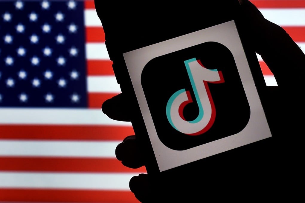The TikTok logo is seen on the screen of a phone with an American flag in the background. Photo: AFP