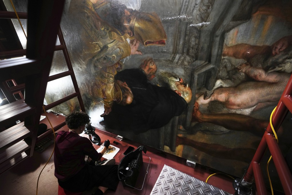 Sitting on a raised platform, art conservator Jill Keppens works on a section of Rubens painting Enthroned Madonna Adored by Saints at the Royal Museum of Fine Arts in Antwerp, Belgium. Photo: AP