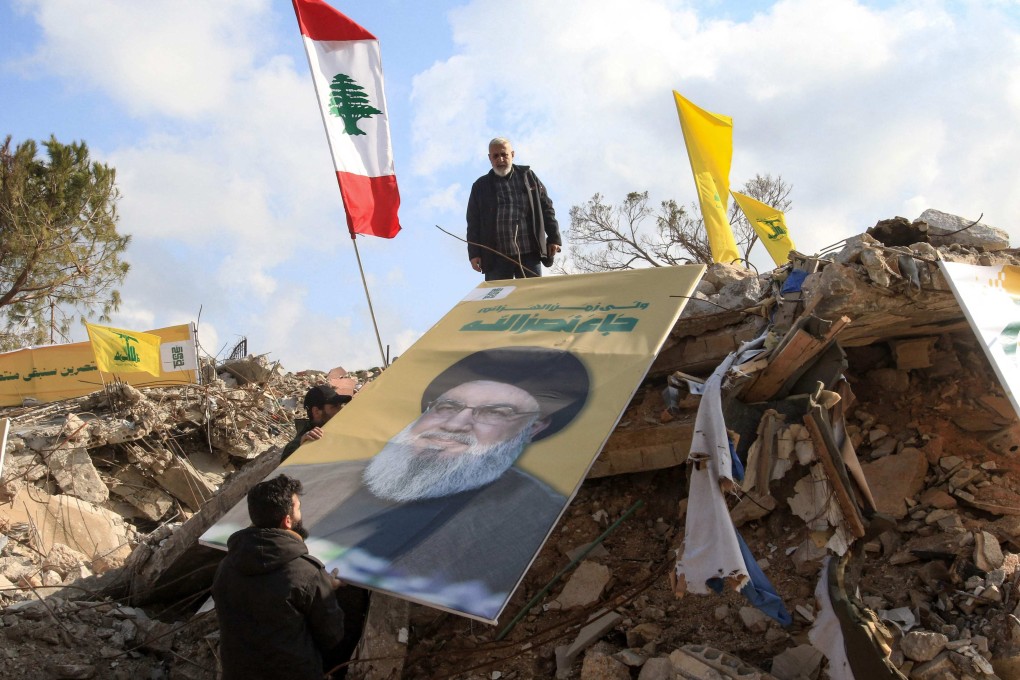 People place a picture of Hezbollah leader Hassan Nasrallah over the rubble of the shrine of Shamoun al-Safa in southern Lebanon’s Tyre region on Friday. Nasarallah was killed on September 27 after a series of Israeli airstrikes in Beirut.  Photo: AFP