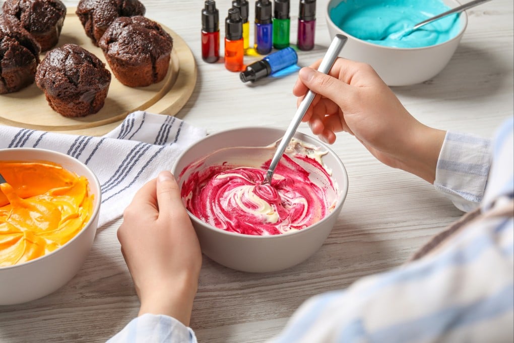 A woman mixes food colouring into cream. Synthetic dyes are added to food to make it appear more natural. Photo: Shutterstock