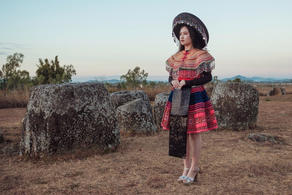 A Hmong woman stands among the ancient stones of the Plain of Jars (Site 1),
outside Phonsavan. The Hmong New Year celebration in Phonsavan, the largest of its kind in Laos, sees young Hmong men and women mix and match traditional attire with modern accessories. Photo: Nicolas Bosoni
