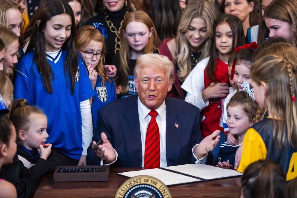 US President Donald Trump surrounded by young female athletes, signs an executive order banning transgender athletes from women’s sports at the White House on Wednesday. Photo: EPA-EFE