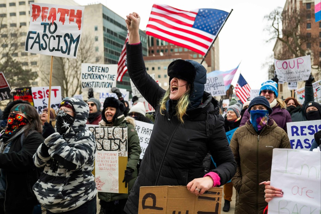 A protester raises her fist as hundreds of people gather on Wednesday on the steps of the Michigan state Capitol in Lansing to protest recent actions taken by the Trump administration. Photo: TNS