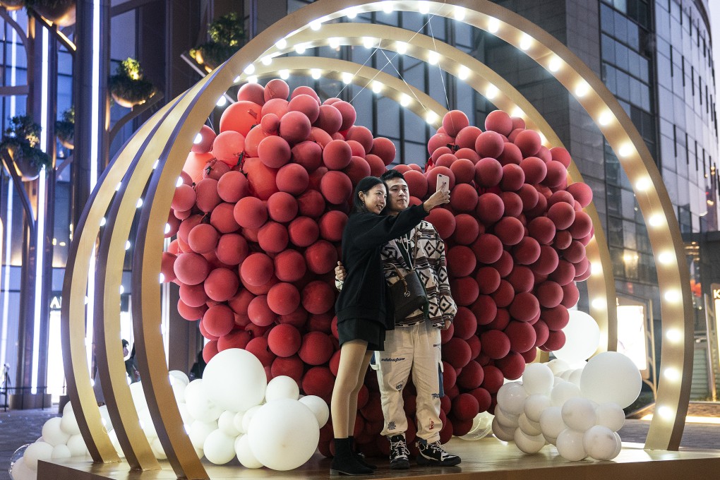 A couple photograph themselves in front of balloons in a heart shape in a shopping mall in Wuhan, central China, on Valentine’s Day in 2021. Photo: Getty Images