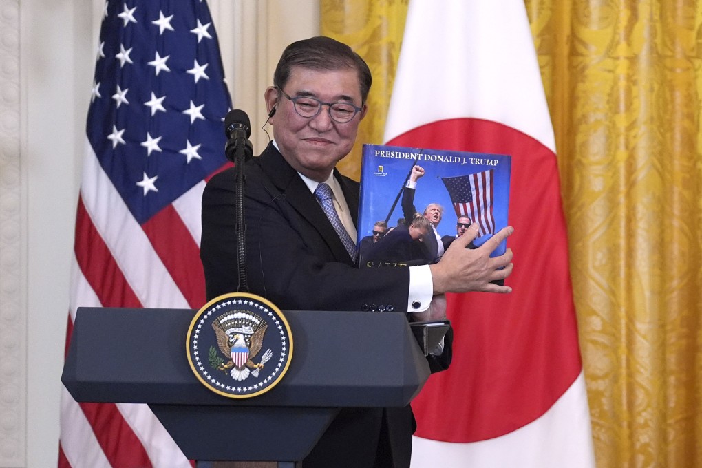 Japanese Prime Minister Shigeru Ishiba holds a book presented to him by US President Donald Trump during a news conference in Washington on Friday. Photo: AP