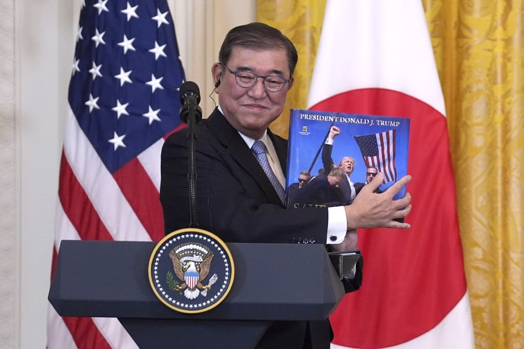 Japan’s Prime Minister Shigeru Ishiba holds a book presented by US President Donald Trump at the White House on Friday. Photo: AP