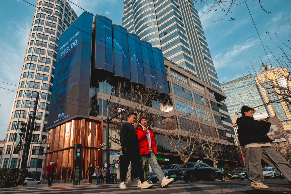 People cross a street near a screen showing stock exchange and economic data in Shanghai. Photo: EPA-EFE