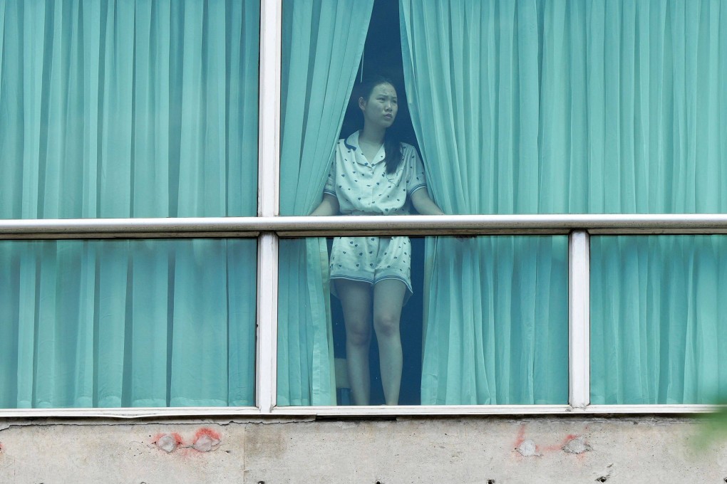 A woman deported from the US looks out the window of the Decapolis Hotel where she is temporarily staying in Panama City. Photo: AFP