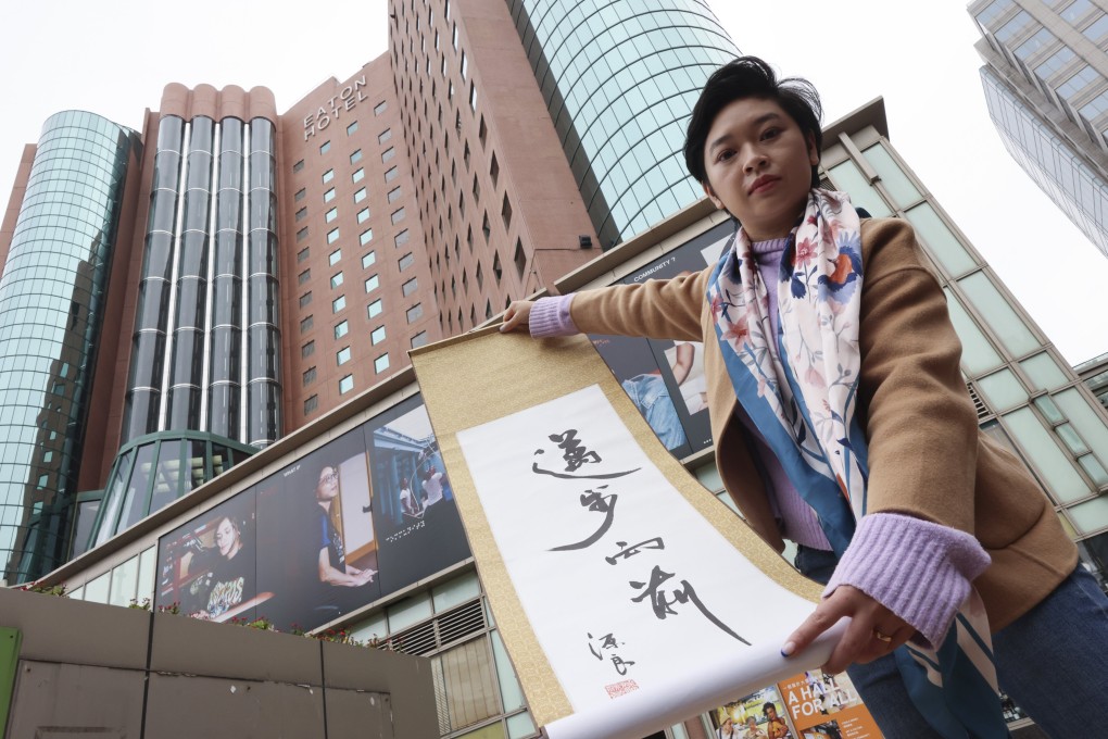 Hong Kong Journalists Association chairwoman Selina Cheng holds up a scroll saying “Moving forward” outside the Eaton Hotel in Jordan. Photo: Jelly Tse