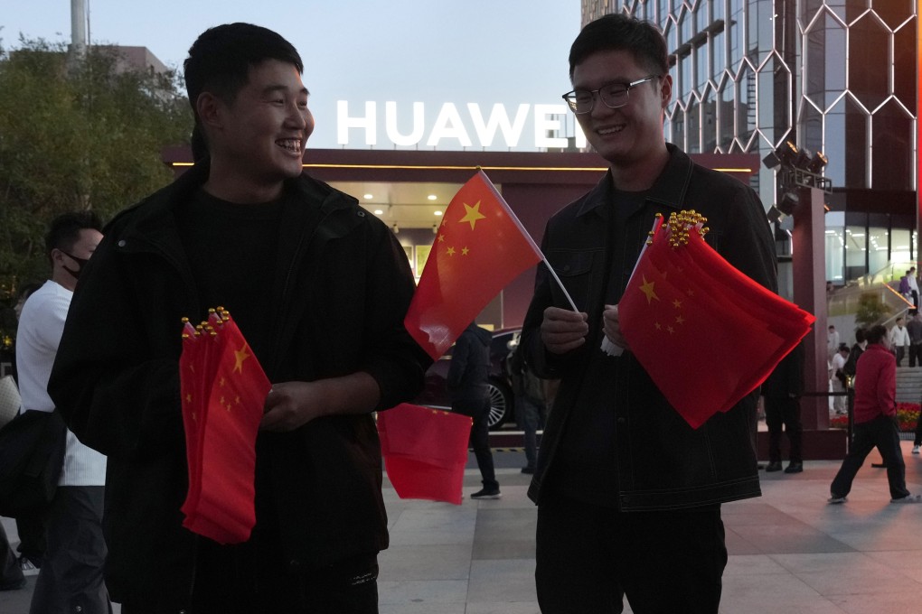 Two men hand out Chinese flags near a Huawei store in Beijing during last year’s National Day holiday. Photo: AP Photo
