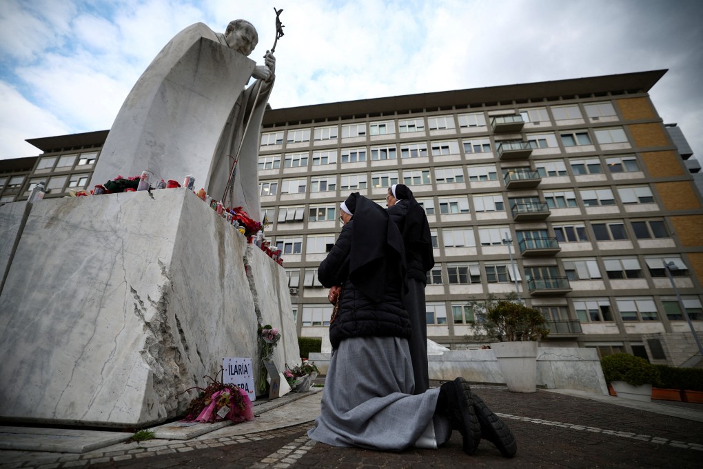 Nuns pray next to the statue of late Pope John Paul II outside the Gemelli hospital where Pope Francis is being treated. Photo: Reuters