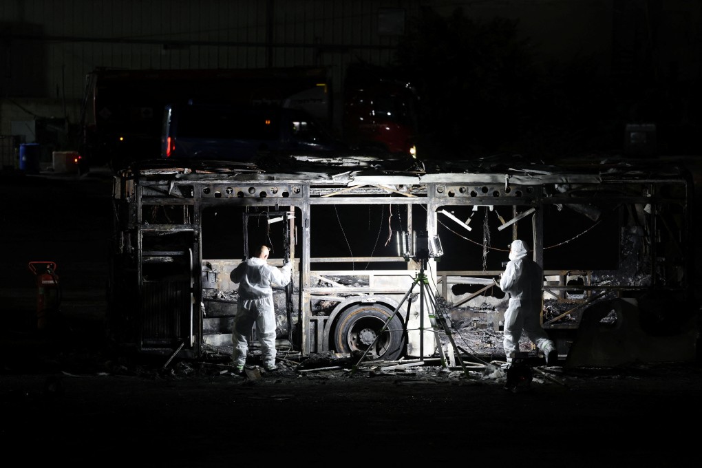Forensics personnel inspect the remains of a destroyed bus. Photo: Reuters