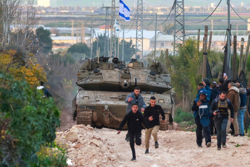 Palestinian children and journalists disperse as Israeli tanks enter the Jenin camp for Palestinian refugees. Photo: AFP