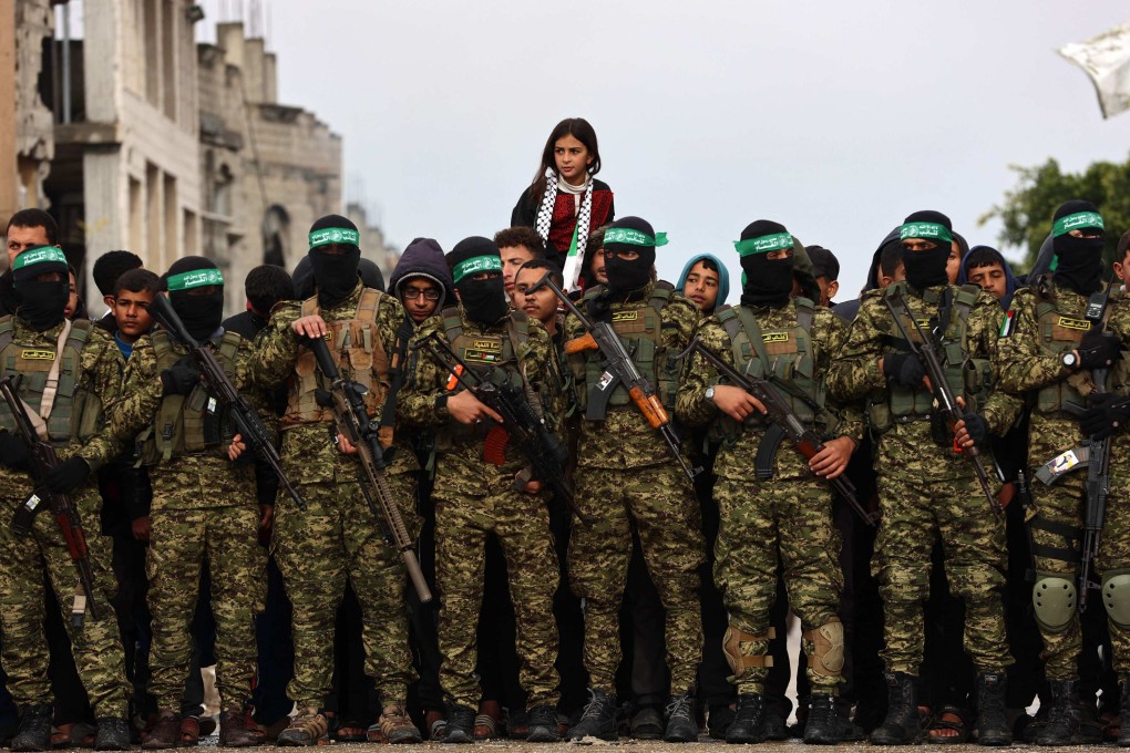 A Palestinian girl is carried on shoulders as Hamas fighters gather at the handover site of Israeli hostages in Rafah in the southern Gaza Strip on Saturday. Photo: AFP