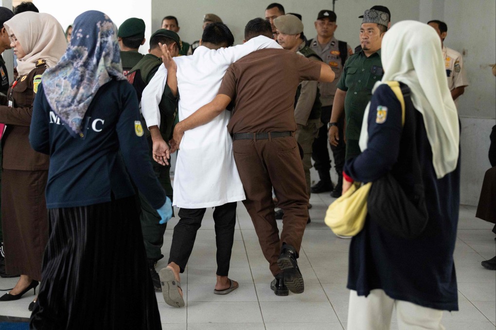 A man (middle, in white), found guilty of sexual relations with another man under the strict Islamic sharia law, is helped after being publicly flogged in Banda Aceh on February 27. Photo: AFP