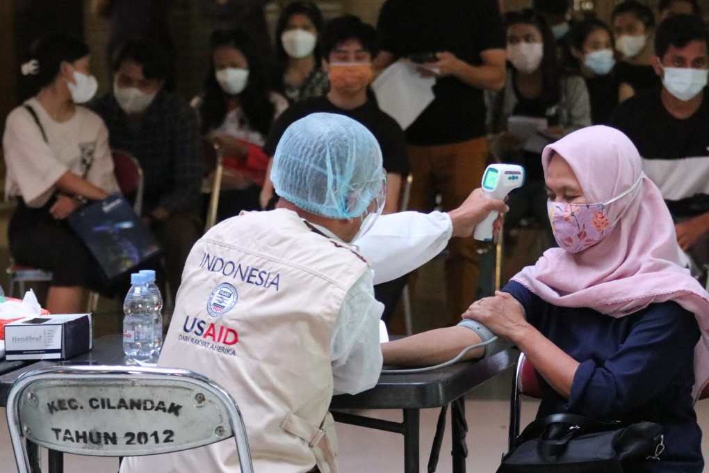 USAID health worker performs a routine health assessment before administering the COVID-19 vaccine to the patient at a mass vaccination clinic in Indonesia in 2021. Photo: USAID