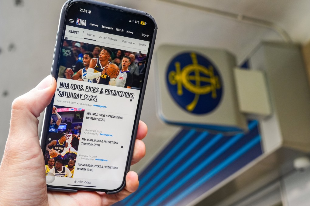 A user holds up the NBABet website on their phone outside a betting station of the Hong Kong Jockey Club. Photo: Eugene Lee