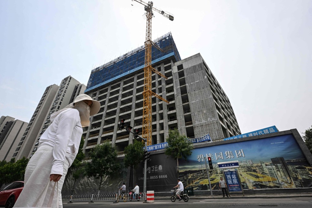 A woman walks past a housing complex under construction in Tianjin, on June 5, 2024. Photo: AFP