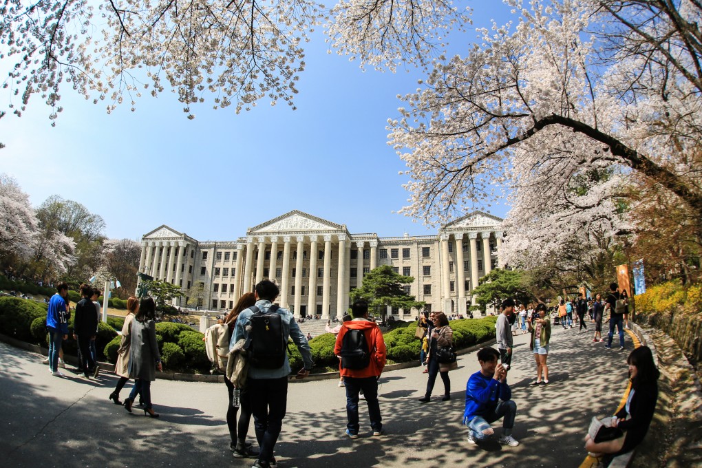 Students walk and take pictures among cherry blossoms at a university campus in Seoul. Photo: Shutterstock