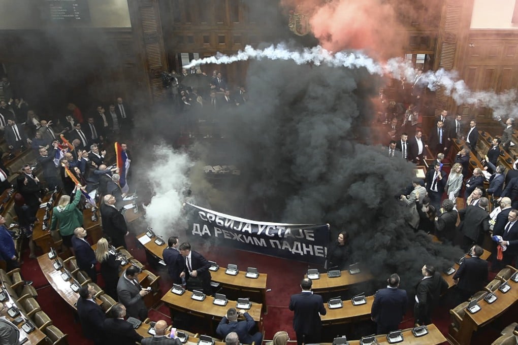 Smoke bombs and flares being tossed in Serbia’s parliament. Photo: RTS Serbia via AP