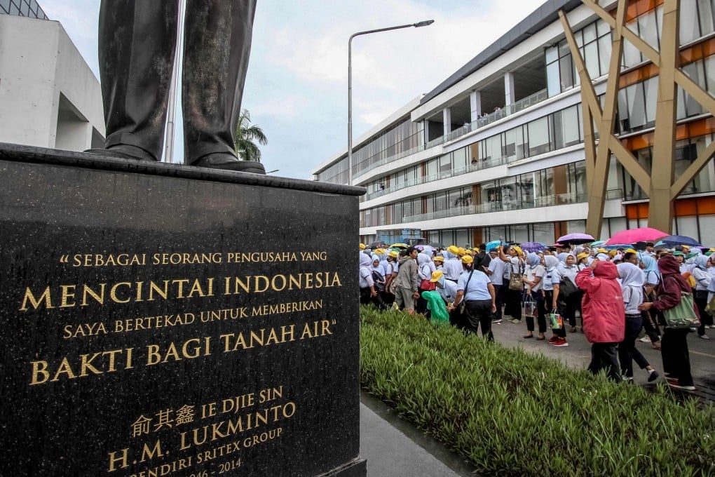 A statue of Sritex founder, Lukminto, is adorned with an inscription reading, “As an entrepreneur who loves Indonesia, I am committed to dedicating my service to the homeland”, while factory workers listen to a farewell speech during mass layoffs, in Sukoharjo, Central Java, on February 28. Photo: AFP
