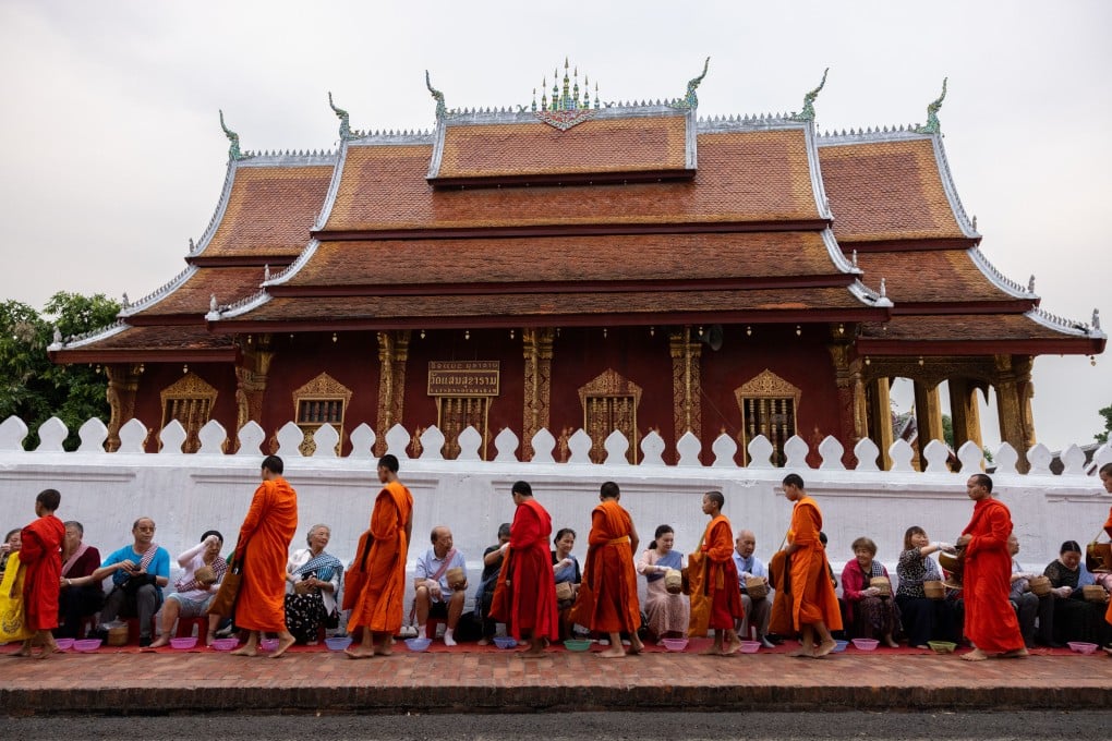 Tourists taking part in an alms-giving ceremony by a procession of monks in Luang Prabang. Photo: Getty Images