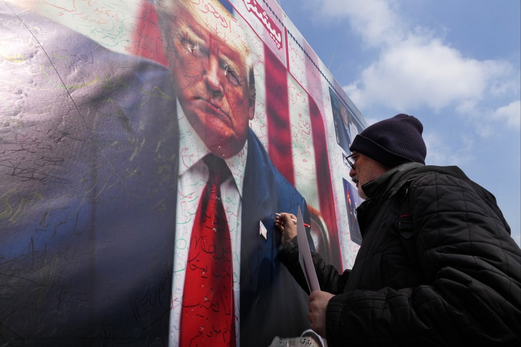 A man writes on a portrait of the US President Donald Trump during a rally commemorating the anniversary of Iran’s 1979 Islamic Revolution that toppled the late pro-US Shah Mohammad Reza Pahlavi and brought Islamic clerics to power, in Tehran on February 10, 2025. Photo: AP