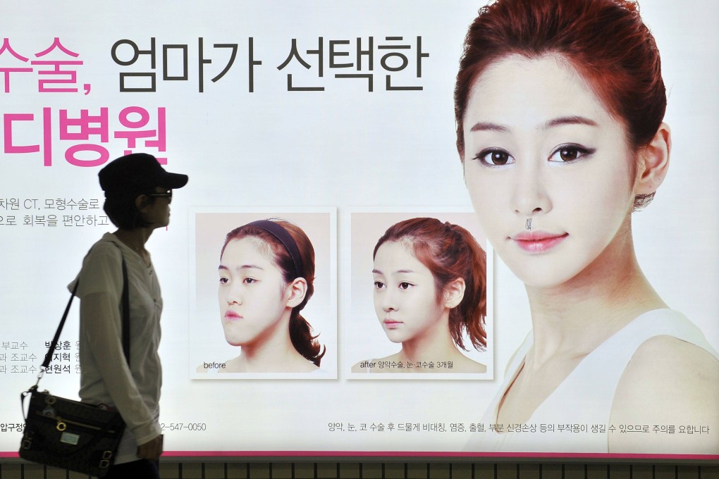 A South Korean woman walking past a street billboard advertising double-jaw surgery at a subway station in Seoul. Photo: AFP