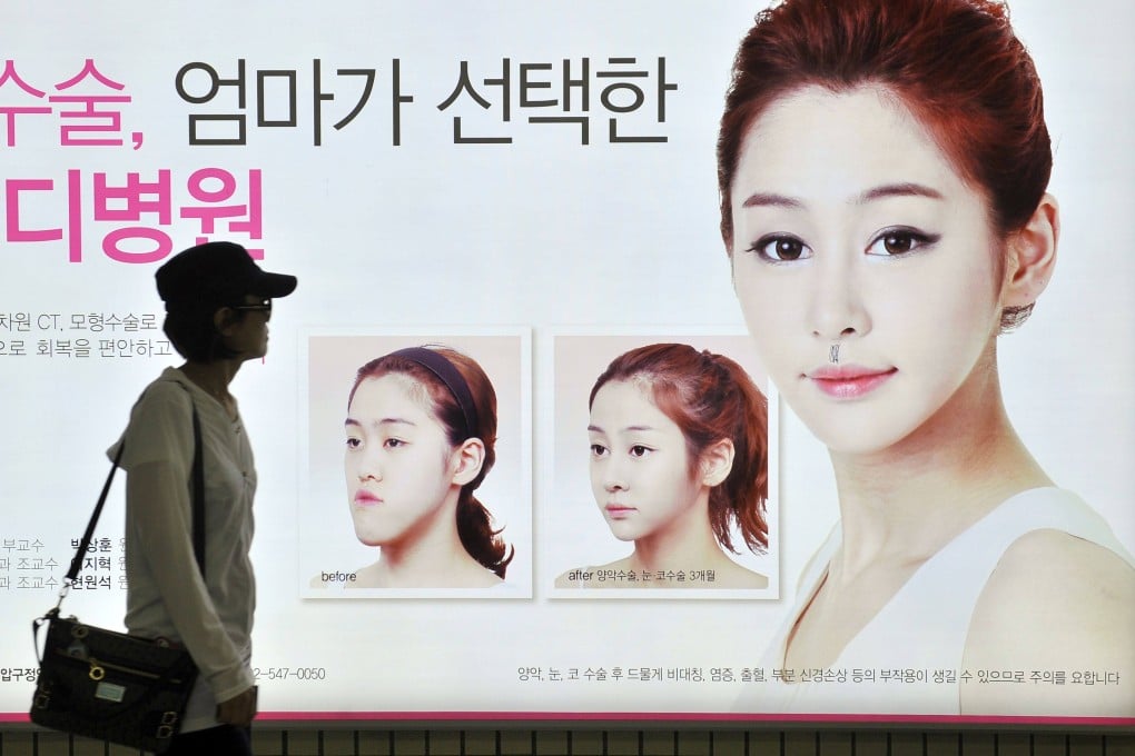 A South Korean woman walking past a street billboard advertising double-jaw surgery at a subway station in Seoul. Photo: AFP