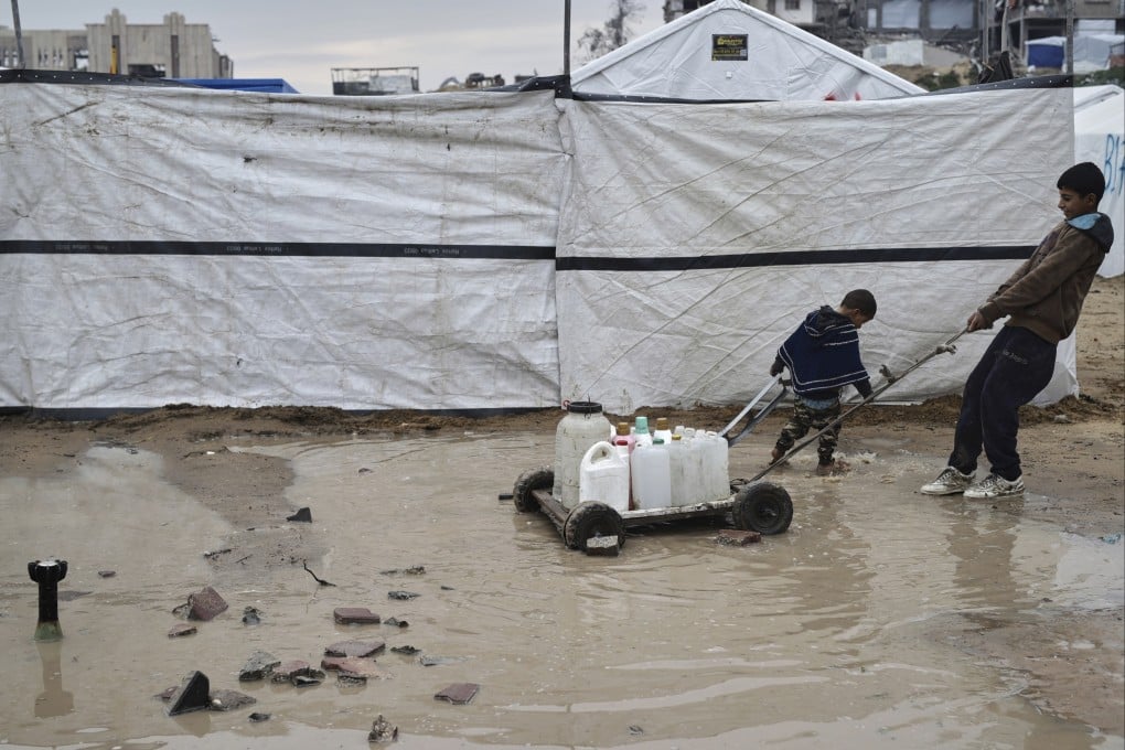 A boy and a child move water in plastic jerrycans in the Zeitoun neighbourhood of Gaza City. Photo: AP