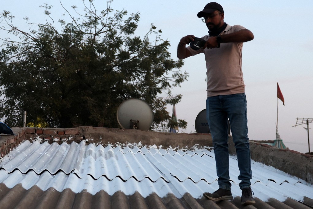 A field supervisor checks the temperature on a rooftop coated with liquid-applied membrane of a slum house in Ahmedabad, India. Photo: Reuters