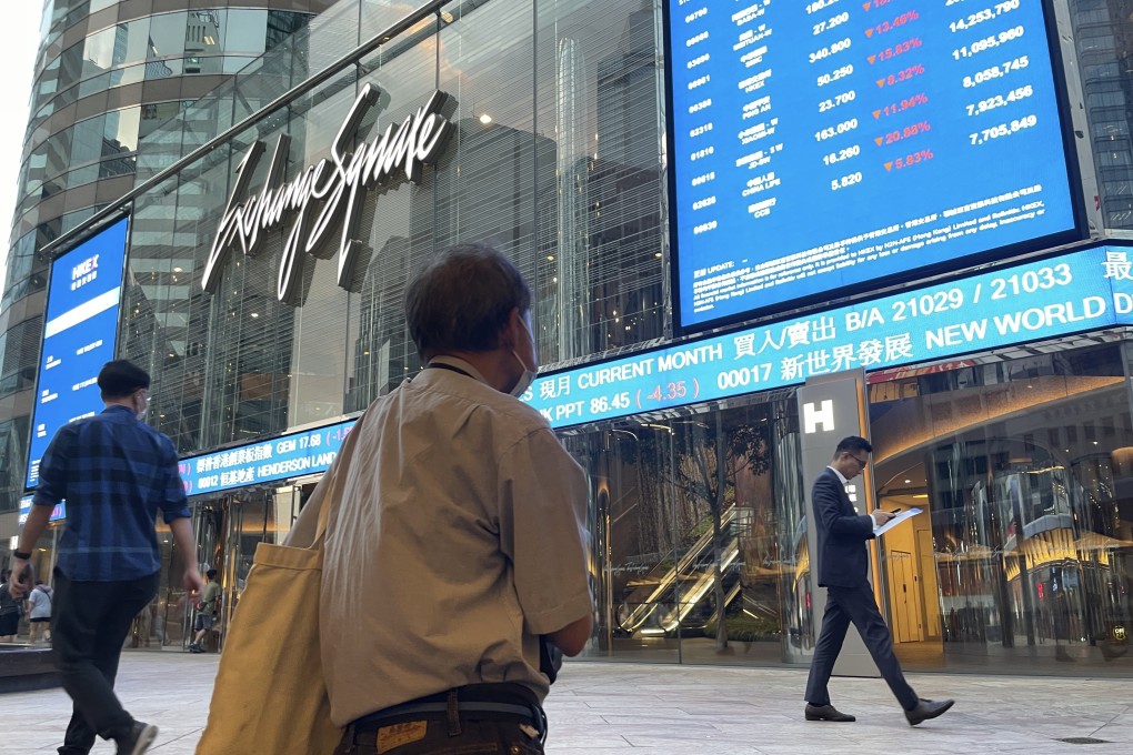 People walk past screens showing Hong Kong’s stock market indicators outside the Exchange Square in Central. Photo: AP Photo