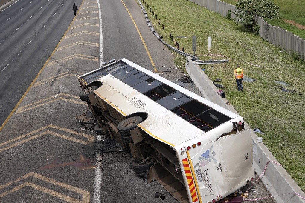 An emergency official walks past a bus that overturned on a highway in Johannesburg, South Africa, killing multiple people and injuring some. Photo: AP