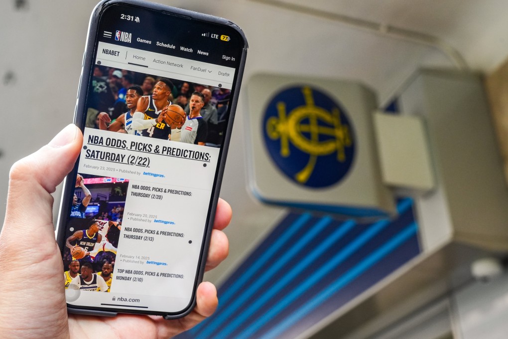 A user holds up the NBABet website on their phone outside a betting station of the Hong Kong Jockey Club. Photo: Eugene Lee