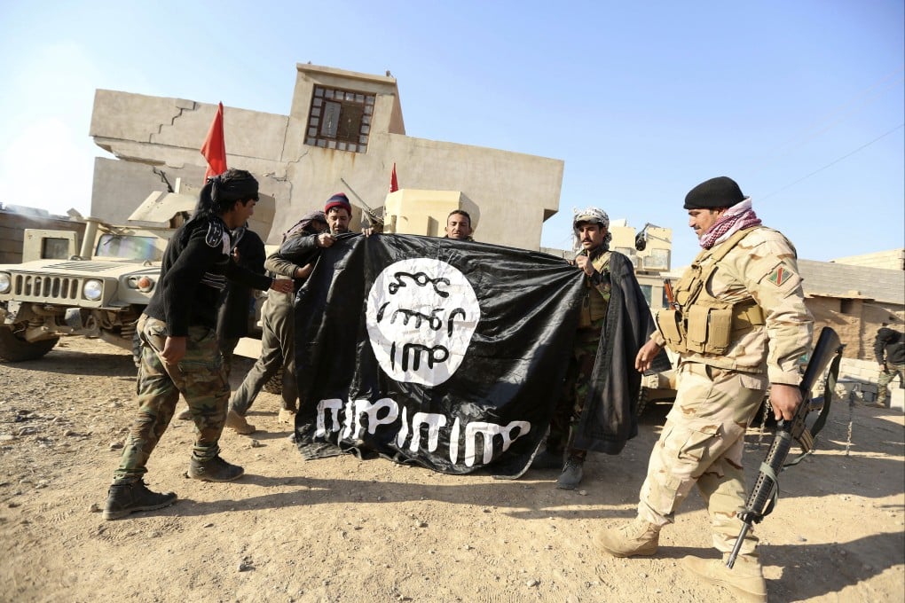 Iraqi Army soldiers hold a flag of Islamic State after regaining control of a village outside Mosul in 2016. Photo: AP