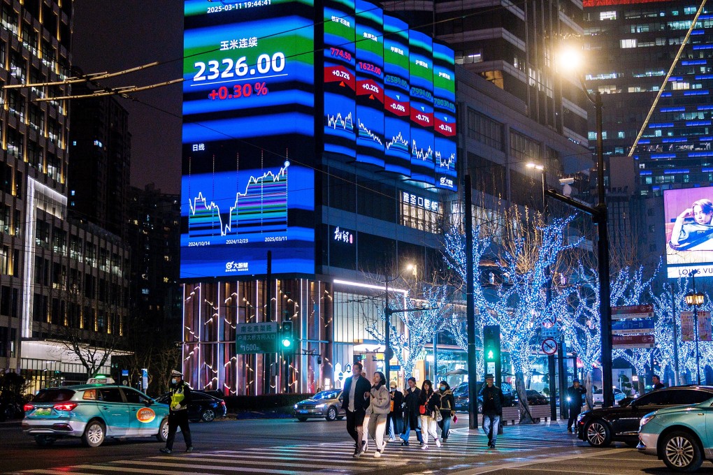 People cross a street in front of a large screen displaying the latest stock market and economy data, in Shanghai on March 11. Photo: EPA-EFE